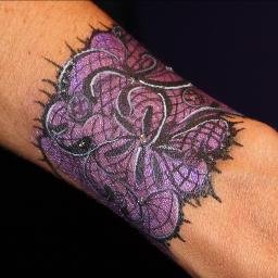 A purple tattoo is on the arm of someone.