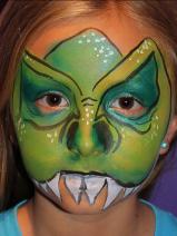 A child with green face paint and teeth.