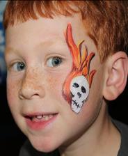 A boy with red hair and orange eyes has a skull painted on his face.