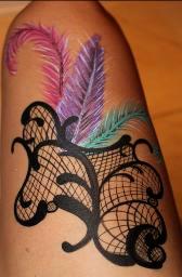 A tattoo of feathers and lace on the arm.