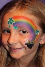 A girl with a rainbow and pot of gold painted on her face.