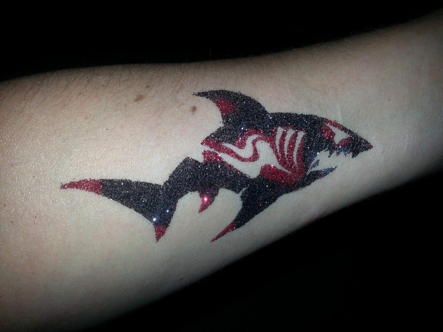 A tattoo of a shark with red and black paint.
