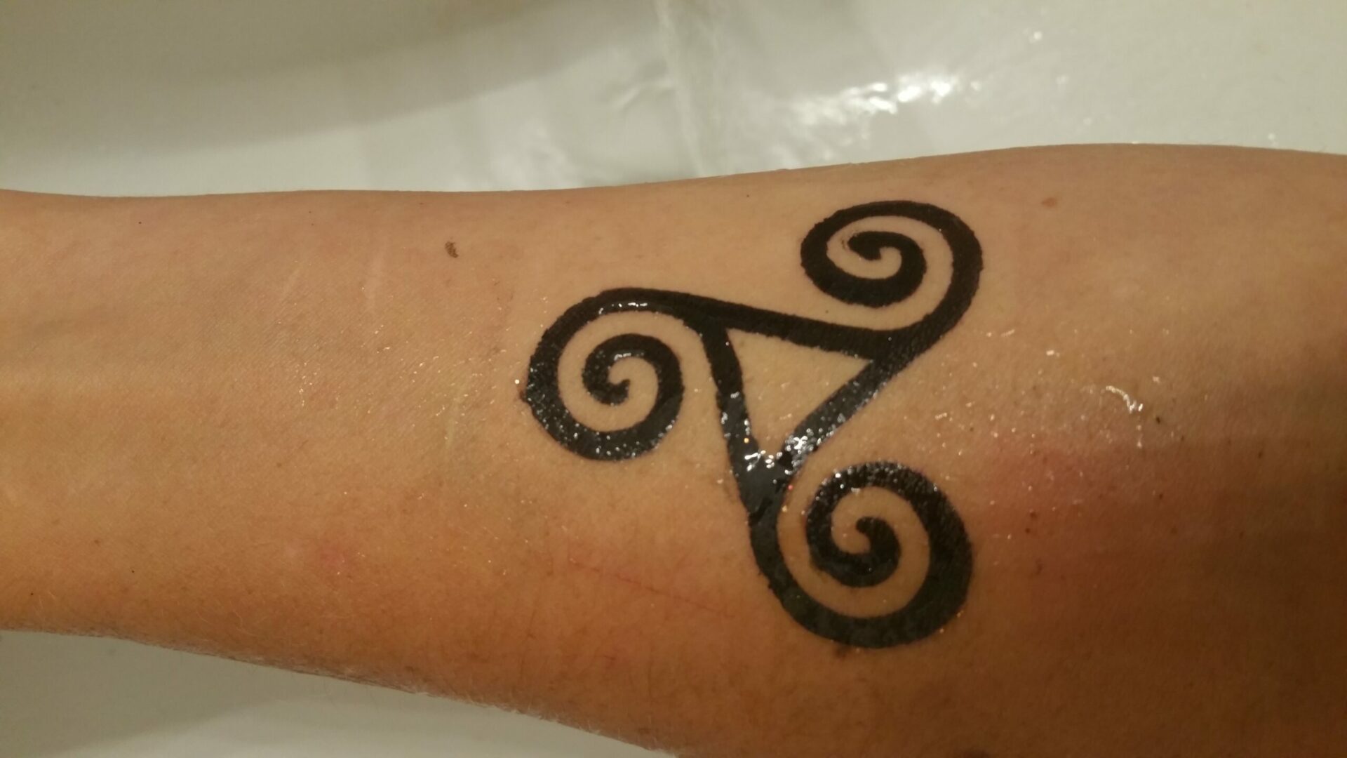 A tattoo of triskelion on the arm.