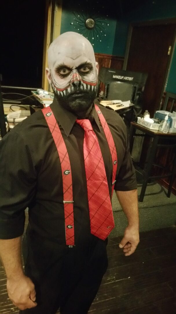 A man with face paint and red tie.