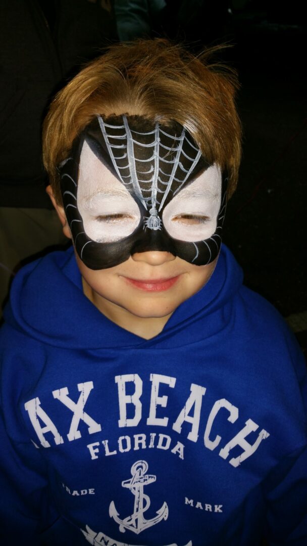 A boy with spider face paint on his face.