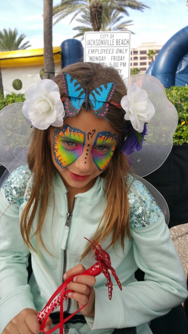 A girl with butterfly makeup and flowers on her head.