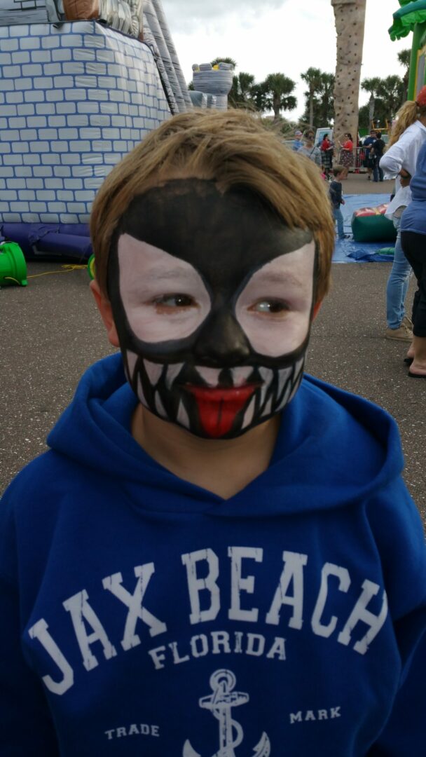 A boy with his face painted like a black cat.