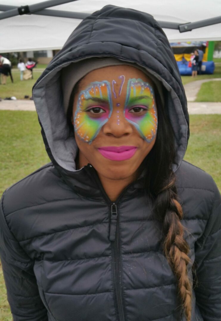 A girl with face paint on her head and jacket.