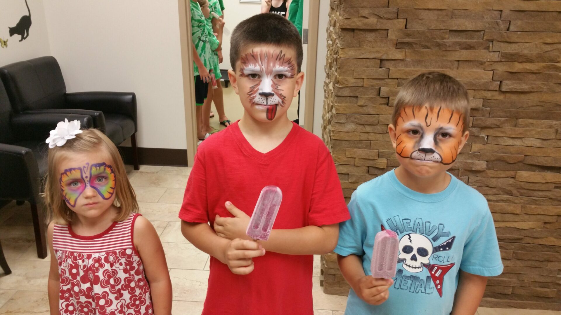 Three children with face paint on their faces.