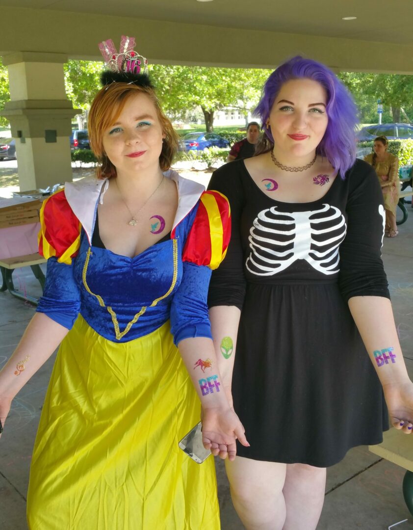 Two women in costumes pose for a picture.