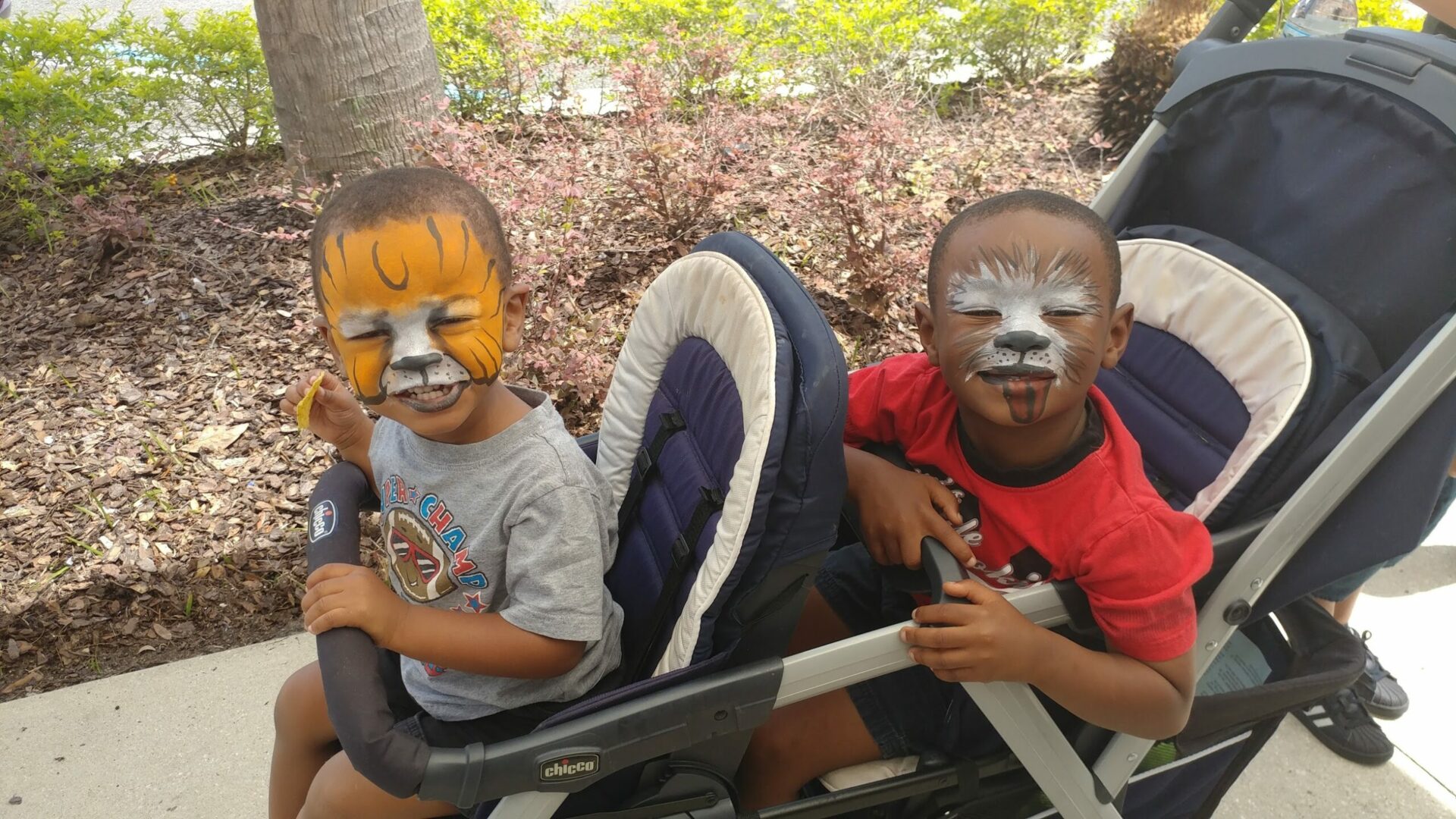 Two children with face paint sitting in a stroller.