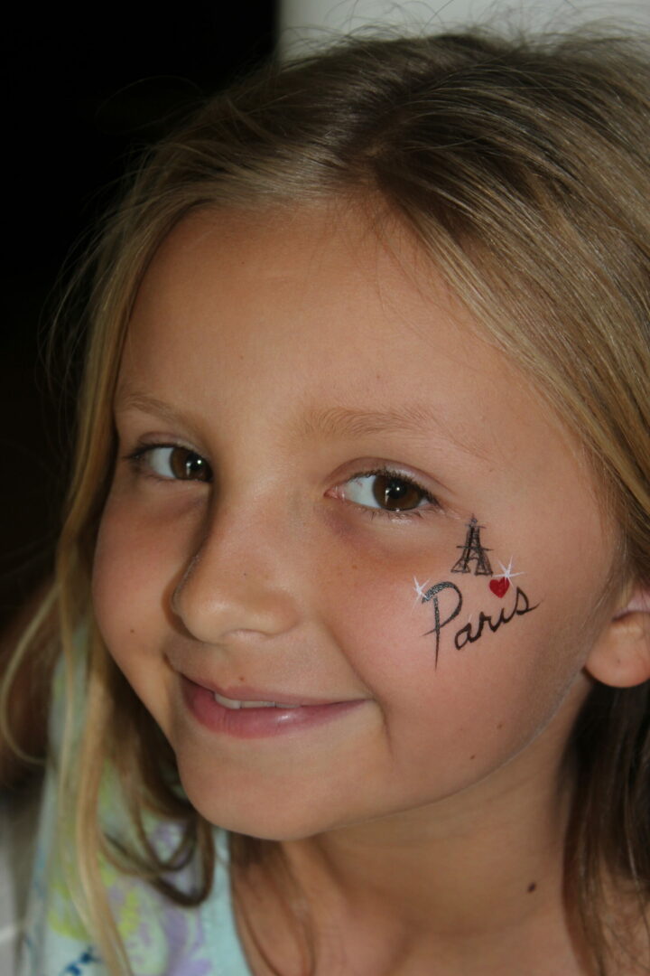 A young girl with paris written on her face.