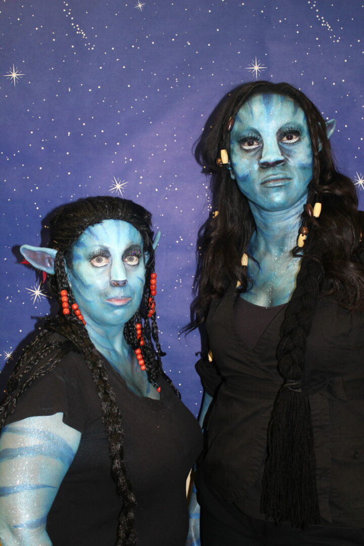 Two women dressed as avatar characters in front of a space background.