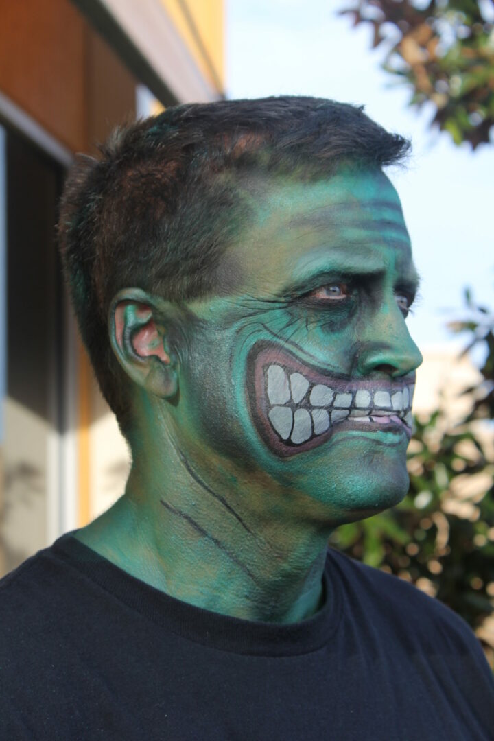 A man with green makeup on his face.