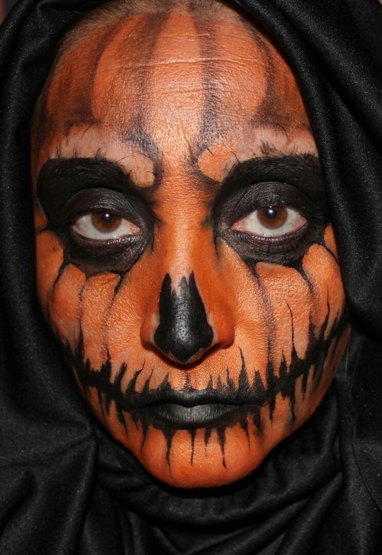 A person with a face painted like a pumpkin.