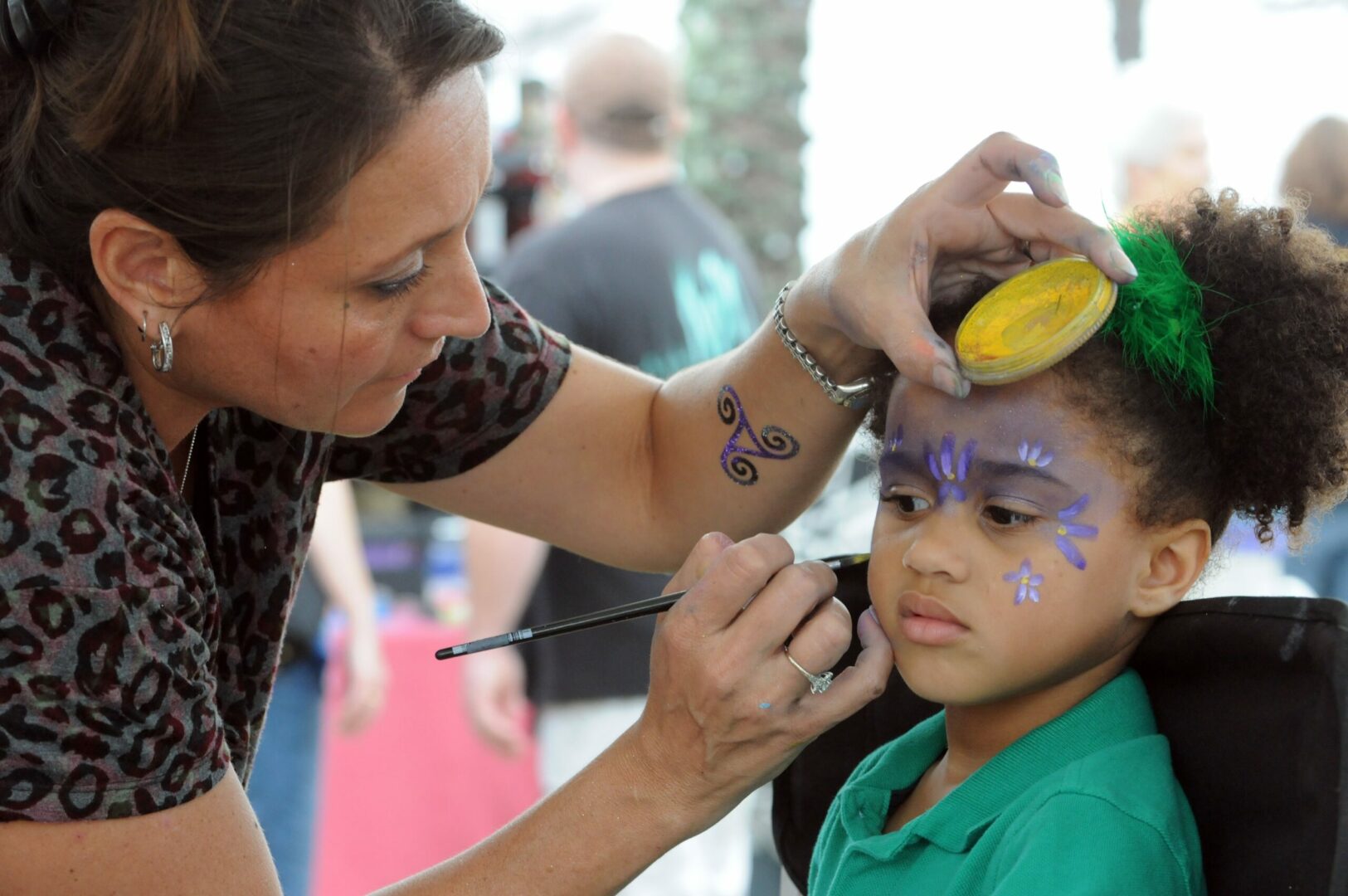 A woman is painting the face of a child.