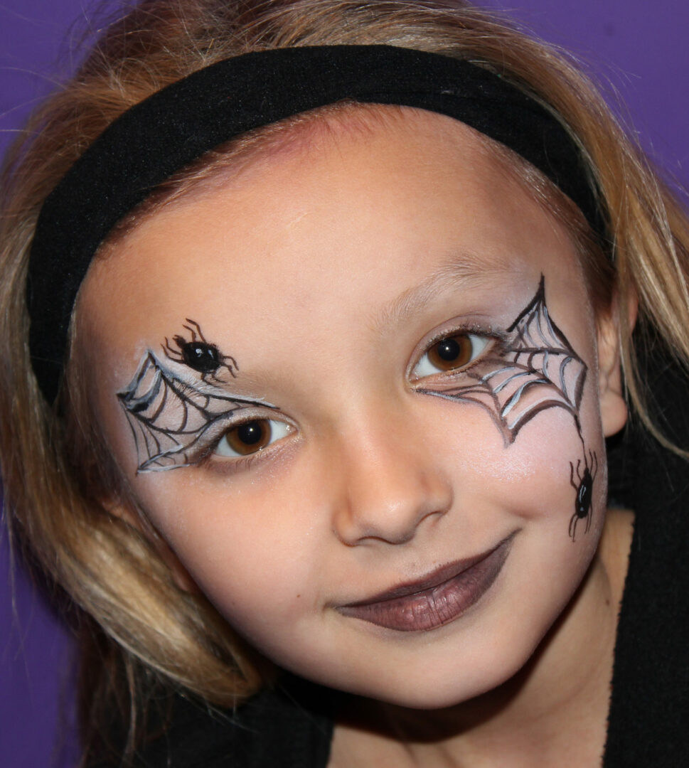 A young girl with spider web makeup on her face.