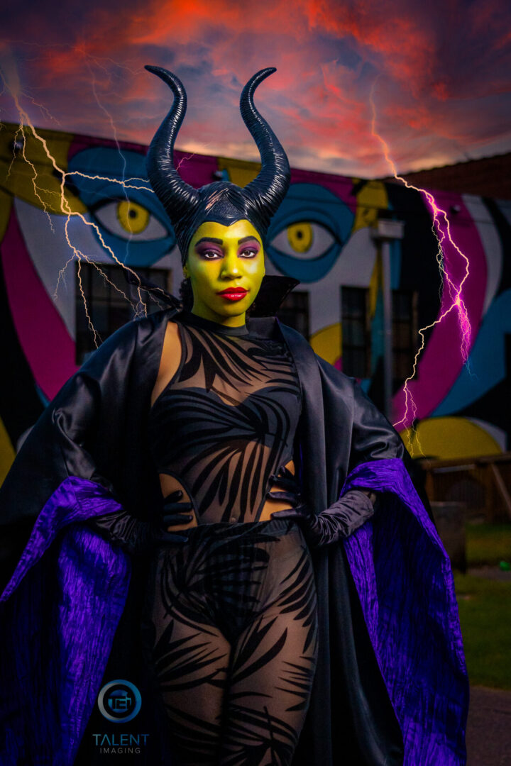 A woman dressed as maleficent in front of a mural.