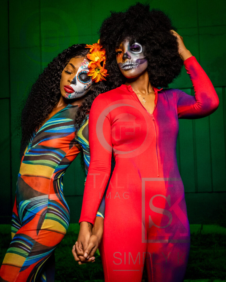 Two women in body paint pose for a picture.