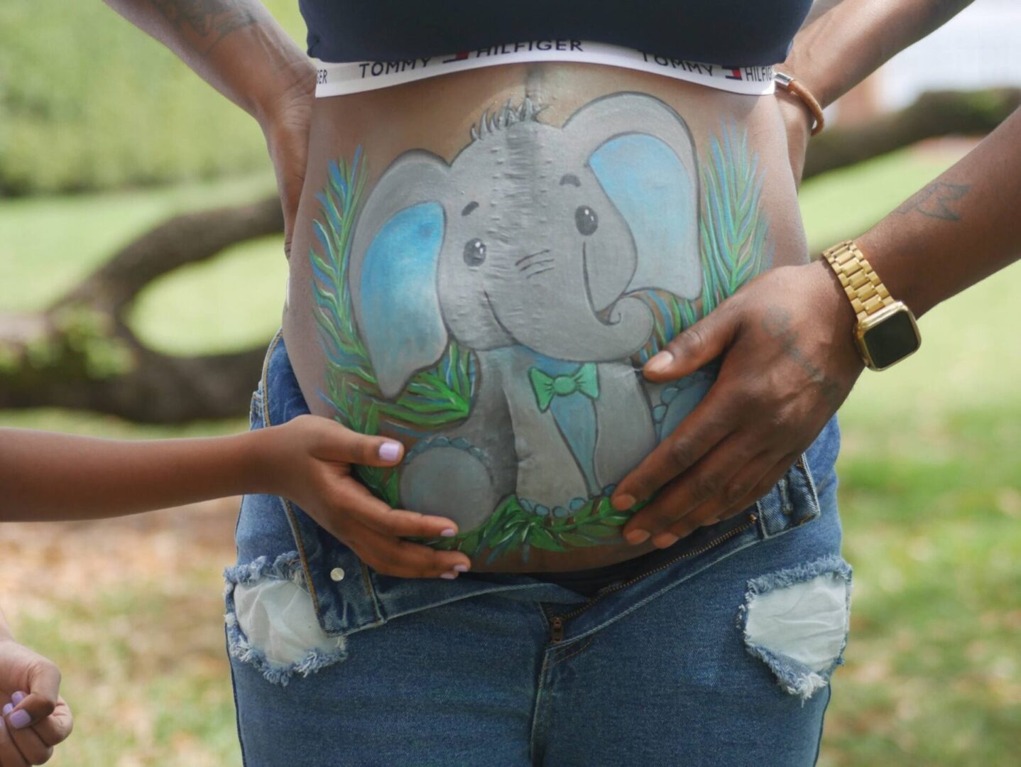 A woman is holding her stomach with an elephant painted.